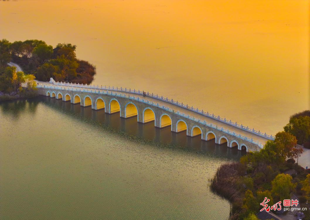 Golden sunlight shines through bridge arches at Nanhu Wetland Park
