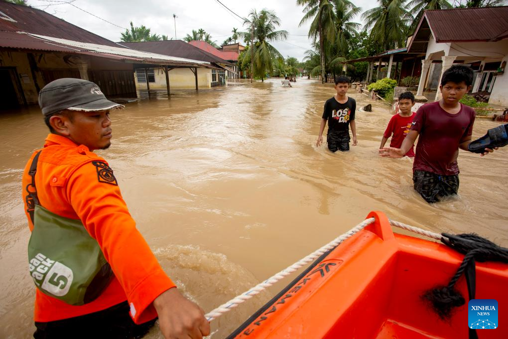 People wade through flood water in Padang Pariaman regency, Indonesia